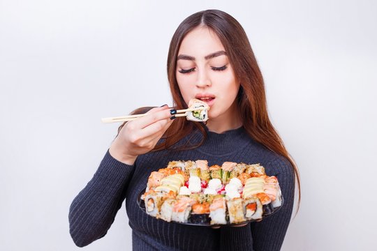 Young beautiful woman eating sushi, studio shoot on white background with copy space. Japanese food