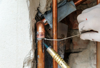 A worker is  soldering copper pipes.