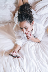 Pretty woman with phone in bed