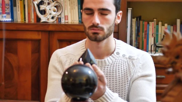 Handsome young man predicting the future by looking into black crystal ball