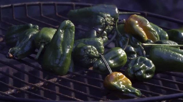 Closeup of padron peppers on a grill in late evening with smoke.