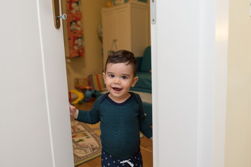 Fototapeta na wymiar Baby boy inside house,opening door to his room