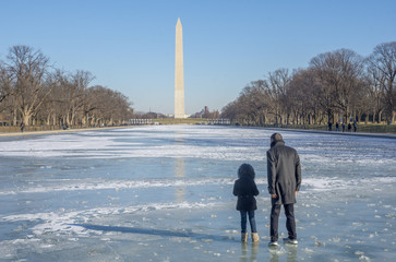 A man and child walk on the frozen reflecting pool of the Lincoln Memorial, turned to ice by many days of sub-freezing temperatures in Washington DC.