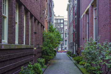 Daytime view of a small, narrow street in the center of Amsterdam, Holland. The walls are in red bricks.