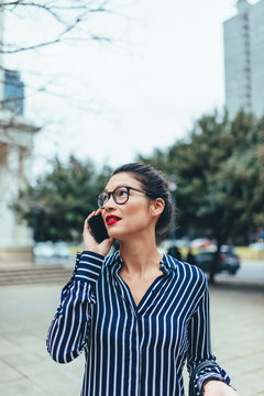 Asian businesswoman walking outside using mobile phone