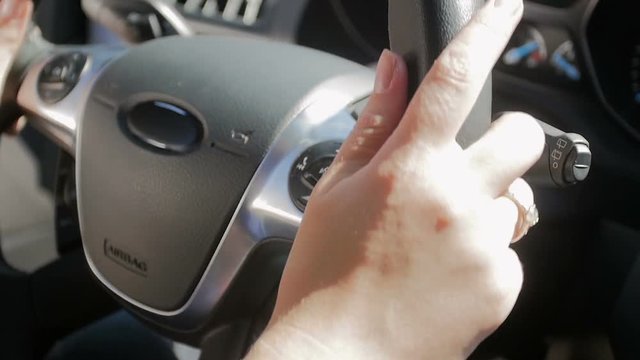Closeup slow motion footage of female drivers hands on car steering wheel