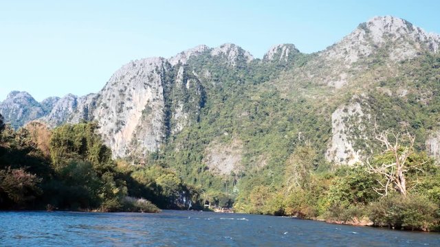 rapid river boat trip with rocky mountains in background slow motion. Vang Vieng, Laos