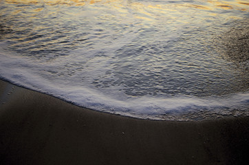 seas as waves crash on the shore on a dar windy morning during tide change