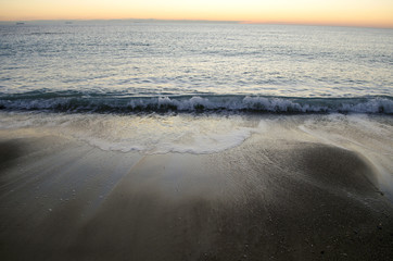 seas as waves crash on the shore on a dar windy morning during tide change