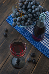 A wineglass of young red Fresh wine with glass bottle and a bunch of black grapes