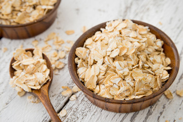 Dry oat flakes or oat grits cereals in craft wooden plate with spoon