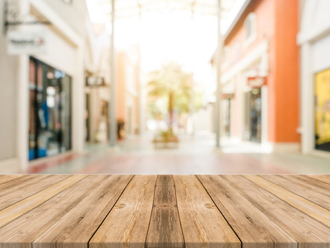 Wooden board empty table blurred shopping mall background. Perspective brown wooden table blur in department store background - can be used for display or montage your products. Mock up for of product