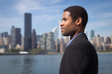 Fototapeta na wymiar Side view of handsome young African American professional, looking at the city skyline across the river