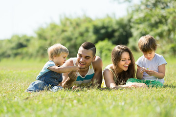 Fototapeta premium Parents with children laying in the grass