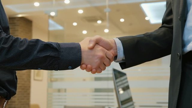 Tilt up of hands of businessman and his colleague shaking hands  at office
