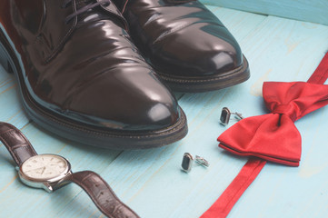 Leather lacquered shoes, bow tie, watch, cufflinks, on a blue background