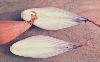 whole and half onions in red on rough wooden background