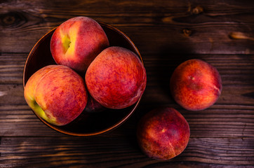 Peaches in a bowl on wooden table. Top view