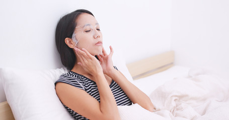 Woman apply paper mask on bed