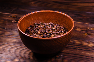 Roasted coffee beans in bowl on wooden table