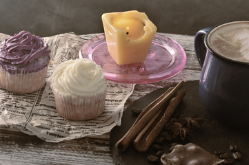 cappuccino in a mug with milk foam and two cupcakes and a candle