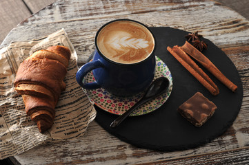 Morning Breakfast at cafe cappuccino in a mug, croissant, cinnamon