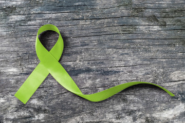 Lime Green ribbon for Lymphoma Cancer and mental health awareness for supporting and helping patient with illness (bow isolated with clipping path on aged wood)
