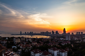 Fototapeta na wymiar View of Old town and Qingdao bay from the hill of XiaoYuShan Park at sunset, Qingdao, China.
