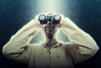 Man in captain hat looks on binocular