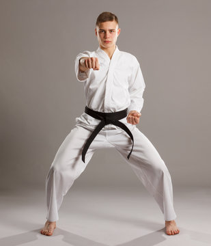 Karate in a fighting pose on the grey background.