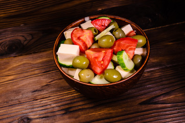 Greek salad in a bowl on wooden table