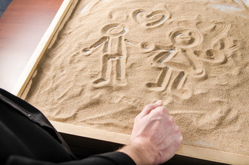 a man is looking on drawn on the sand figures of a man and a woman with a symbol of the heart above them