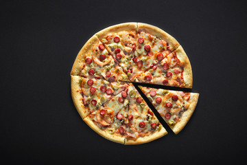 pizza with sausages on black stone background