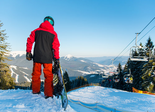 Full length rear view shot of a snowboarder standing in the mountains looking around enjoying beautiful winter day at ski resort copyspace sportsman sport seasonal recreation concept Bukovel