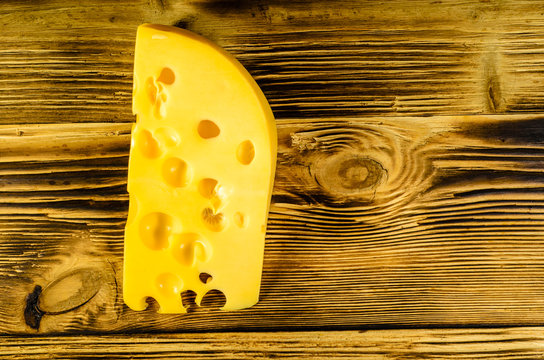Piece of cheese on wooden table. Top view