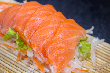 Close up raw fresh salmon sashimi set salad  on black table.