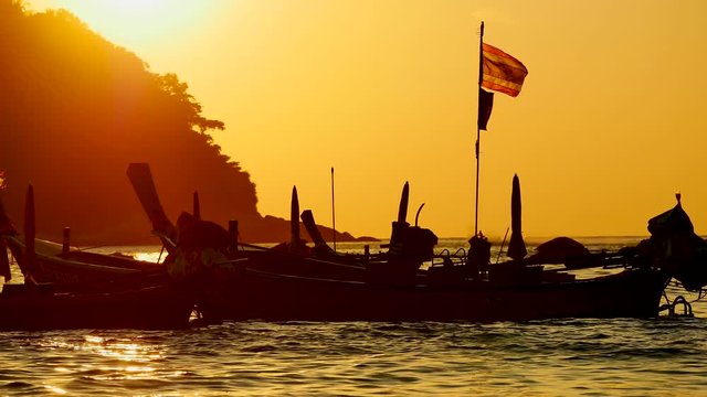 Group of long tail boat or boat excursions floating in the andaman sea with golden light of sunset and  boat background in travel or transportation concept.