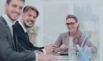 Happy business people looking at camera in office and  using com