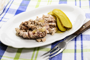 grilled pig brain with onions and gherkin served on a plate