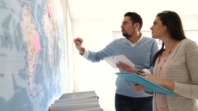 Colleagues in office looking at world map