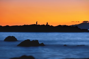 Humans silhouette on the reef at suset slow shutter 