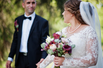 Romantic lovely newly married couple posing in the park by the medieval castle on their wedding day.