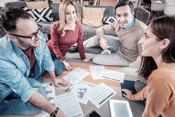 New ideas. Satisfied joyful creative colleagues sitting in the office on the floor communicating and talking about documents.