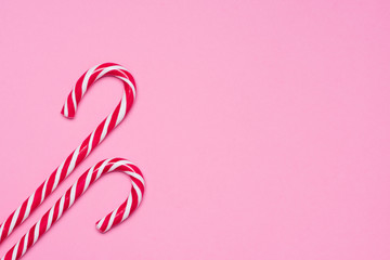 Two candy canes on pink background top view with copy space