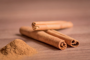 cinnamon sticks and powder on wooden table. Soft focus