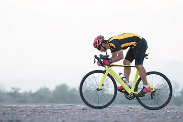 Naklejka premium Road bike cyclist man cycling. Biking sports fitness athlete riding bike on an open road to the sunset.