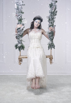 Woman in snow queen costume on swing