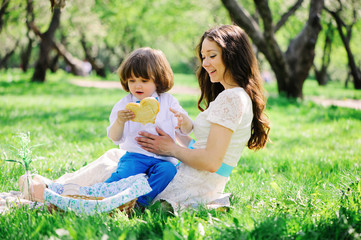 happy family on picnic for mothers day. Mom and toddler son eating sweets outdoor in spring or summer park.