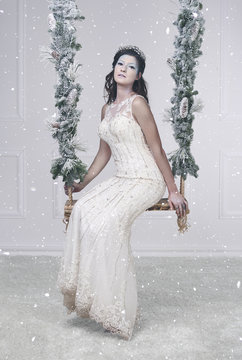 Pretty ice queen on swing among falling snow