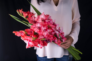 woman holding a beautiful bouquet of flowers from pink gladiolus